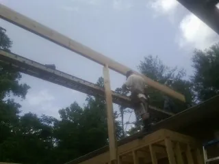 Carpenter setting a ridge beam over a new addition frame — Ice Dam Removal by Roofing Brothers in Niagara
