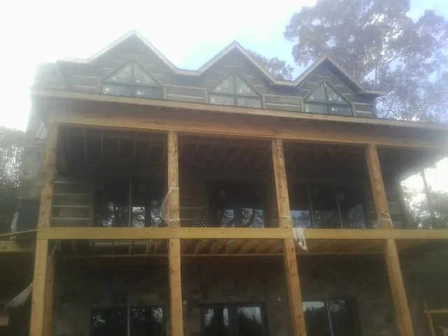 Dormers and porch framing on a large log home under construction — Roof Coating work by our crew in Niagara