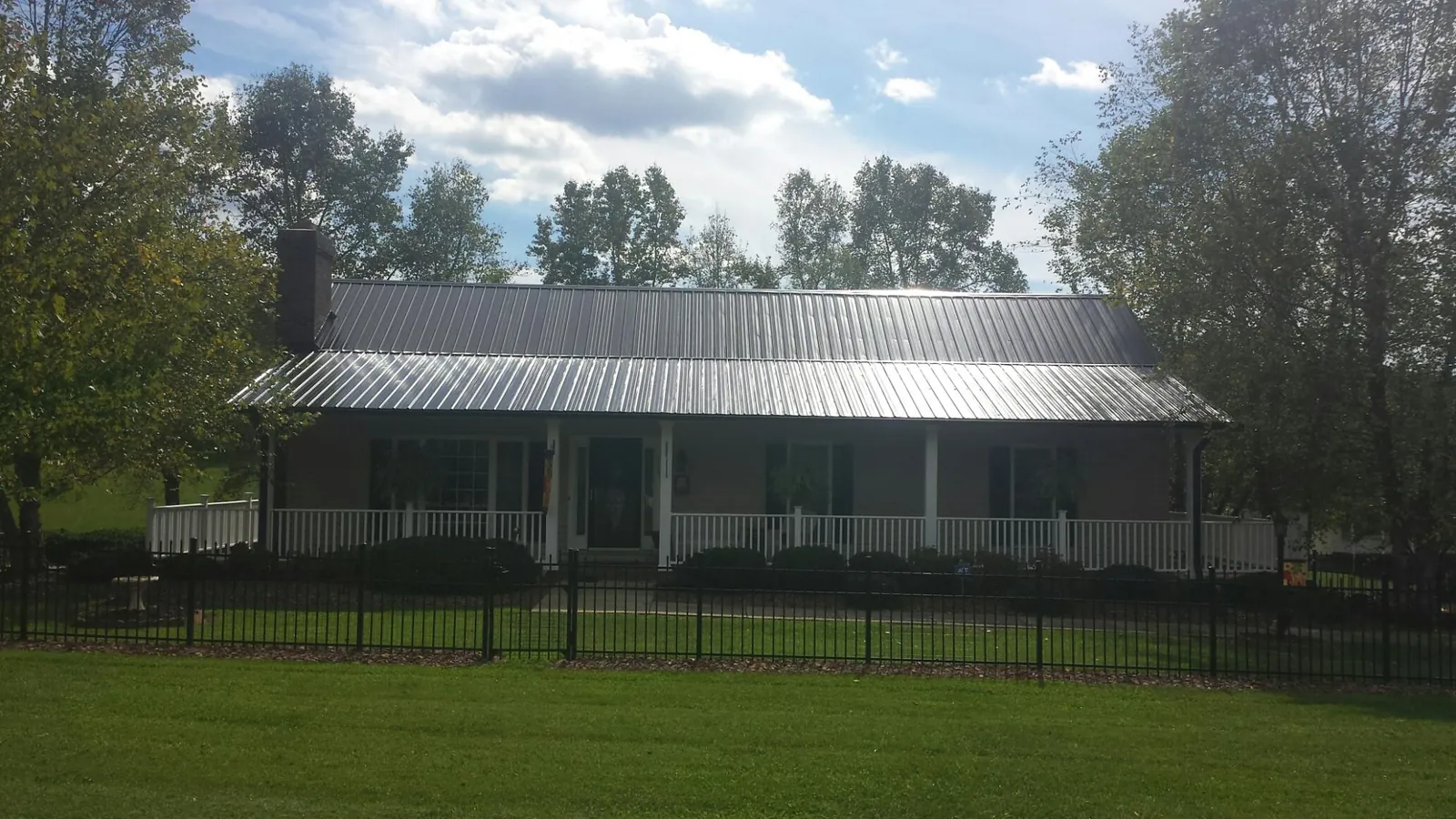 Gray metal roof on a brick ranch with a full width front porch — Gutter Guard Installation work by our crew in Niagara
